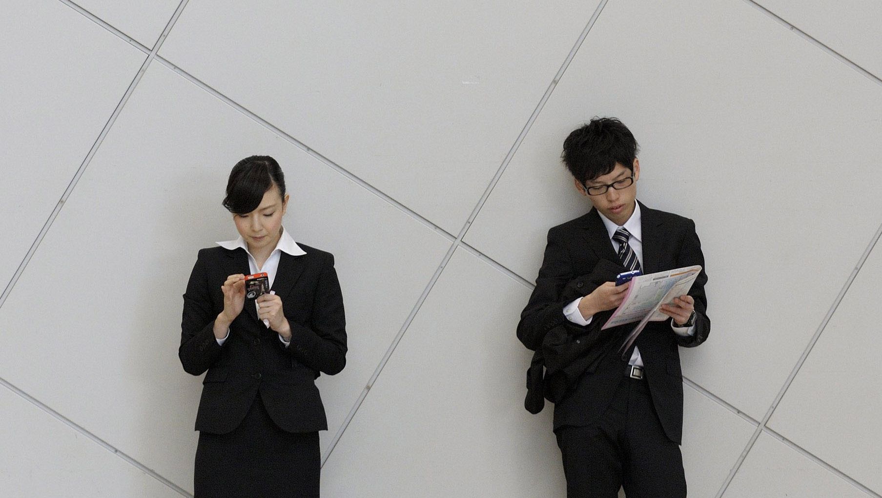 In touch: University students use smartphones at a job fair in Tokyo in December. Firms starting to see value in hiring grads who have studied overseas