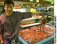 A store owner holds aloft a crab at one of Otaru’s seafood markets. Tourists are now the big catch for reborn Otaru