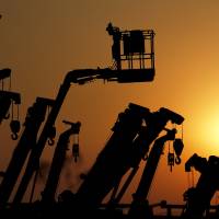 Looking up: Cranes and booms stand are silhouetted in January at a Tokyo equipment rental firm near a construction site. The government said Wednesday that industrial output picked up in February, upgrading its basic assessment of the economy for second straight month. Outlook upgraded for a second month