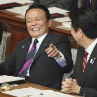 Seriousness aside: Finance Minister Taro Aso (left) has a light moment with Prime Minister Shinzo Abe during Thursday’s Lower House plenary session. Aso vows 'drastic' action on deflation