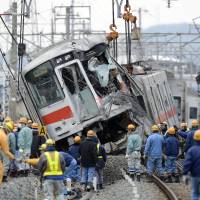 Unscheduled stop: Workers haul away a derailed Sanyo Electric Railway Co. train Wednesday in Takasago, Hyogo Prefecture. Truck driver held over train wreck