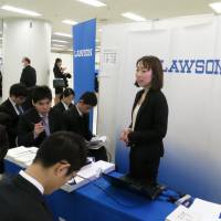 Mining a new resource: An official at convenience store chain Lawson Inc. draws a big crowd during a recruitment forum for international students studying in Japan on Feb. 19 in Tokyo’s Ikebukuro district. Firms go abroad by hiring foreign students here
