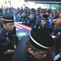 Another casualty: Malaysian police officers carry a coffin containing a dead police commando killed during a standoff with Sulu gunmen in Tanduo village, near Lahad Datu, shortly after it arrived at Subang Royal Malaysian Air Force Base in Kuala Lumpur on Saturday. Fresh clashes in Borneo siege leave seven more dead