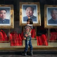 Historical figures: A girl stands before portraits of former Chinese leaders Zhou Enlai, Mao Zedong and Liu Shaoqi in Beijing at the end of February, ahead of a key parliamentary meeting of China’s top leaders in the capital this week. Chinese labor camps to face scrutiny as top leaders meet