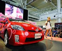 Strikes a chord: A model struts past Toyota Motor Corp.'s DecoPrius, adorned with rhinestones, crystals and stickers, during a promotional event July 20 at the automaker's showroom in Odaiba, Tokyo. Carmakers chase female buyers