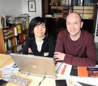 Ansgar vollmer and Yoshiko Tajima pose in their condominium in Shinjuku Ward, Tokyo, on Feb. 17. Below are book covers for Asahi Shinsho and a corporate logo they created. Pair practice art of collaboration in life, work