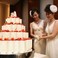 Dream come true: Koyuki Higashi (left) and Hiroko cut the cake at their wedding reception at Tokyo Disney Resort in Chiba Prefecture on Friday. Lesbian couple get Disney 'wedding'
