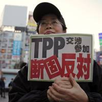 TPP foe: A protester holds a sign reading “We oppose Japan’s participation in the TPP talks” during a Thursday rally in Tokyo against the Trans-Pacific Partnership accord. Abe declares Japan will join TPP free-trade process