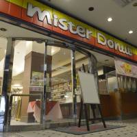 A man stands in front of a Mister Donut store in Toyonaka, Osaka Prefecture, in March, 2013. Mister Donut store serves bleach in water