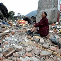 Reduced to rubble: A woman whose relatives were killed in Saturday’s earthquake cries while sitting on a pile of rubble in Lingguan township in Baoxing County in southwest China’s Sichuan Province on Sunday. China rushes relief as Sichuan quake toll hits 188