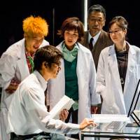 Mr. Efficiency: Ken (Kosuke Toyohara, front) explains the logic of business operation efficiency to two young scientists, chief officer Grant (Suu Nakajima, at rear) and senior scientist Iffy (Yuko Miyamoto, right) in “The Opportunity of Efficiency.” Welsh approach to 'national' theater is efficiently different