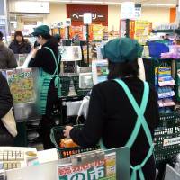 Cash or charge?: Female part-time workers man the checkout lines at a supermarket in Nakano Ward, Tokyo, on Friday. Tax, pension breaks called favoritism for homemakers