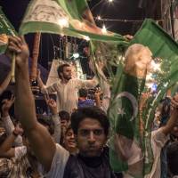 Green grins: Supporters of the Pakistan Muslim League-N party celebrate election results in Lahore on Saturday. Sharif claims historic win in Pakistan polls