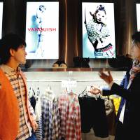 Showtime: Salesclerk Shohei Sugiyama (right) shows a customer how to turn on a video by picking up a hanger with an embedded sensor at the Vanquish store in Shibuya Ward, Tokyo, on April 19. High-tech hangers offer shopping tips