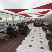Waiting in style: Passengers wait for their flights in the outdoor patio of the Delta airlines Sky Club at terminal 4 at JFK airport on Friday in New York. The expanded concourse offers sweeping views of the airport, upscale food and shopping options and increased seating. It replaces a decrepit terminal built by Pan Am in 1960 that was an embarrassing way to welcome millions of visitors to the United States. Delta ups ante in battle for New York fliers with $1.4 billion terminal