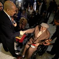Giving back: Newark Mayor Cory Booker (left) shakes hands with Willie Wilkins after returning a box with Wilkins World War II dog tags, which he lost in France during the war, at an event to return them to the veteran on May 8 in Newark, New Jersey. The event, which was held as a surprise for Wilkins, 90, also marked the 68th anniversary of V-E Day, the end of World War II in Europe. Record as Newark mayor weighs heavily on Booker Senate bid