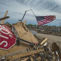 Tornado alley: An American flag flies over a mound of debris in a neighborhood in Moore, Oklahoma, on Thursday. Soon after a killer tornado blew through the town, in the suburbs of Oklahoma City, a few days before, residents began displaying flags as symbols of hope and unity. Storm chasers ride the winds undaunted by danger