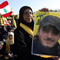 In mourning: A Hezbollah supporter in the village of Mashghara, Lebanon, on Saturday holds a poster of her son, who was killed during a battle in Syria 40 days earlier. Hezbollah fighters 'invading Syria'