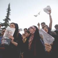 Young at heart: Supporters of Iranian presidential candidate Hasan Rowhani hold campaign posters during a street rally at Vanak Square in Tehran on Wednesday. Iran poll shows waning clerics' clout
