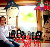 Local color: Kite- maker Satoru Yamaya (top) reveals his infectious sense of humor in a train-kite series of the pylori bacterium that can cause ulcers and lead to cancer. Baker Yuzaburo Kanehara (above) bears his signature bear cookie. Portions of the covered corridor at Igusa Hachimangu shrine (below) were made with timber from an ancient pine that once grew in the precincts. Where whimsy meets wonder