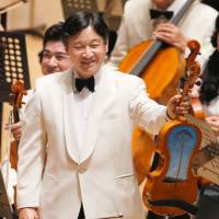 No ordinary driftwood: Crown Prince Naruhito displays a viola Sunday at a concert held by Gakushuin University alumni in Tokyo. The viola was partially built from a pine tree hit by the March 2011 tsunami in Rikuzentakata, Iwate Prefecture. Crown Prince plays viola made of tsunami debris