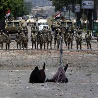 Between a rock: Egyptian supporters of deposed President Mohammed Morsi sit in front of barbed wire fencing blocking access to the headquarters of the Republican Guard in Cairo on Monday. Islamists call for uprising after army kills dozens in Cairo