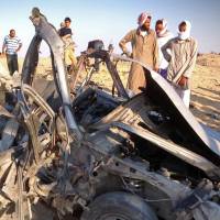 Free-fire zone: Egyptians gather Wednesday around the wreckage of a vehicle after a car bomb detonated and killed three passengers near the North Sinai town of el-Arish. Two soldiers died in separate shootings the same day in the area. Egypt insurgency takes root in Sinai
