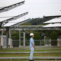Time and energy: An employee stands in front of concentrator photovoltaic units at Sumitomo Electric Industries Ltd.’s new power plant in Yokohama in July 2012, when the firm demonstrated its megawatt-class power generation/storage system. Can a battery jolt economy?