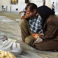 In grief: In this authenticated photo provided by the Local Committee of Arbeen in Damascus, a man and woman mourn over dead bodies Wednesday after an alleged poisonous gas attack perpetrated by pro-regime forces in a suburb of Syria’s capital. Ban calls for access to Syrian attack site