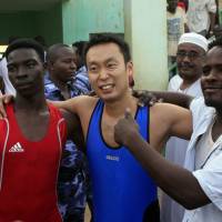 Barefoot diplomacy: Yasuhiro Murotatsu (center) poses with Sudanese fighter Saleh Omar Bol Tia Kafi after losing their traditional Nuba wrestling match in Khartoum on Aug. 28. Diplomat wrestles for peace in riven Sudan