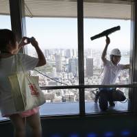 Something to see: A woman visiting the special observation deck at Tokyo Tower in Minato Ward photographs a window cleaner on Tuesday. A broken window on an elevator serving the deck, 250 meters above ground, forced a shutdown the same day. Boy, 6, hurt in Tokyo Tower mishap