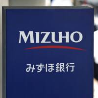 Criminals’ bank of choice: Pedestrians walk by a sign for Mizuho Bank in Tokyo. Financial regulators on Friday ordered the mega-bank to stop lending money to yakuza. Loans to yakuza must stop, FSA warns Mizuho