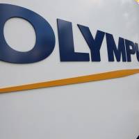 One down, 22 to go: A man walks past an Olympus Corp. logo outside the company’s showroom in Tokyo earlier this month. Scandal-tainted Olympus said Friday it has reached the first in a series of shareholder settlements related to lawsuits filed at home and abroad over its accounting scandal in 2011. Olympus reaches first shareholder settlement over accounting scandal