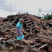 Scrap and flinders: A woman walks amid the wreckage of her home in the Agua Caliente district of Acapulco on Friday. Mexico turns to rebuilding after deadly storms