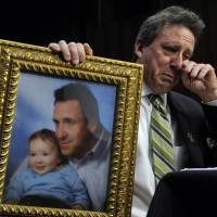 Unspeakable sadness: Neil Heslin, the father of a 6-year-old boy who was slain in the Sandy Hook massacre in Newtown, Connecticut, on Dec. 14, holds a picture of himself with his son, Jesse, while testifying before the Senate Judiciary Committee on Capitol Hill in Washington in February. Gun-violence victims often greeted by silence