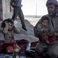 Friend or foe?: A Free Syrian Army fighter holds his son outside their home in Habit, Hama province, on Wednesday. Syrian rebel groups ally to create Islamic state, reject West