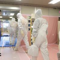 Exercise in control: Prime Minister Shinzo Abe (left) sees off Tokyo Electric workers leaving to patrol storage tanks for radioactive water on Sept. 19 after visiting the emergency operation center of the utility’s wrecked Fukushima No. 1 power plant. Abe looks to retain nuclear power in nation's basic energy policy