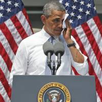 Exasperated: President Barack Obama wipes sweat from his face during a June speech about climate change at Georgetown University in Washington. U.S. shutdown obscured rocky debut of 'Obamacare'