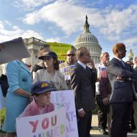 On the outside looking in: Protesters display placards during a demonstration in front of the U.S. Capitol in Washington on Tuesday urging Congress to pass the budget bill. Democrats find rare unity in budget fight