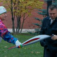 In the flick of time: A security officer lights an Olympic torch for former swimming champion Savarsh Karapetyan after the flame was blown out in Moscow on Sunday. Russian President Vladimir Putin ceremoniously lit the Olympic flame on Red Square earlier in the day, but the four-month relay to Sochi for the Winter Games got off to a rocky start when one of the torches went out. Flame goes out in Moscow's Olympic torch relay