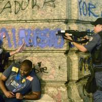 Taking aim: A police officer points a tear gas gun at demonstrators during protests over teachers’ working conditions and police brutality on Tuesday in Rio de Janeiro. Ahead of World Cup, inequities ignite ire in Brazil