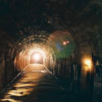 Shining light on a dark time: A guide enters the tunnels under Keio University’s Hiyoshi campus in Yokohama. WWII tunnels beneath Keio campus under threat