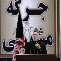 Defiant: Afghan President Hamid Karzai delivers a speech on the first day of the Loya Jirga in Kabul on Thursday. An aid to Karzai said he plans to defy U.S. threats to sign a bilateral security deal before spring elections. Afghan president holds firm on delaying security deal with U.S.
