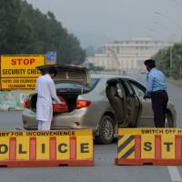 Hidden danger: A Pakistani policeman searches a car at a checkpoint on Constitution Avenue in Islamabad on Oct. 29 Pakistani extortionists cash in by posing as Taliban