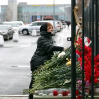 In remembrance: A woman lays flowers at a list of the plane crash victims at the international airport in Kazan on Monday. A Boeing 737 operated by a Russian airline crashed there the previous day while attempting to land, killing all 50 on board. Video showing Russian jetliner's vertical crash emerges
