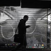 A man looks at his cellphone as he walks in downtown Madrid on Thursday after allegations emerged that Spain was a target for surveillance by the NSA. Eyes everywhere: 9/11 attacks transform once underfunded NSA into an all-seeing technological powerhouse
