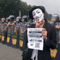 No-go: An Anonymous protester wearing a Guy Fawkes mask is blocked by riot police during a rally calling for Internet freedom held in Manila last November. Hackers expose holes in Asia Web