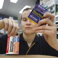 Night capsules: An employee at a pharmacy holds up packages of popular over-the-counter sleeping medications. Should we put the sleep-aids debate to bed?