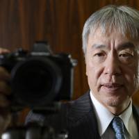 Still clicking: Hiroyuki Sasa, president and chief executive officer of scandal-tainted Olympus Corp., poses for a photograph with the OM-D E-M1 camera in Tokyo on Dec. 18. Sales of mirrorless models are growing at Olympus. Mirrorless cameras offer glimmer of hope to makers