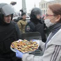 Food for thought: A pro-European Union activist tries to give food to riot police officers preparing to block the Independence Square in Kiev on Monday. Organizers called on protesters to vacate City Hall and another building the opposition had used as its headquarters. EU's Ashton to fly to restive Ukraine for two-day visit